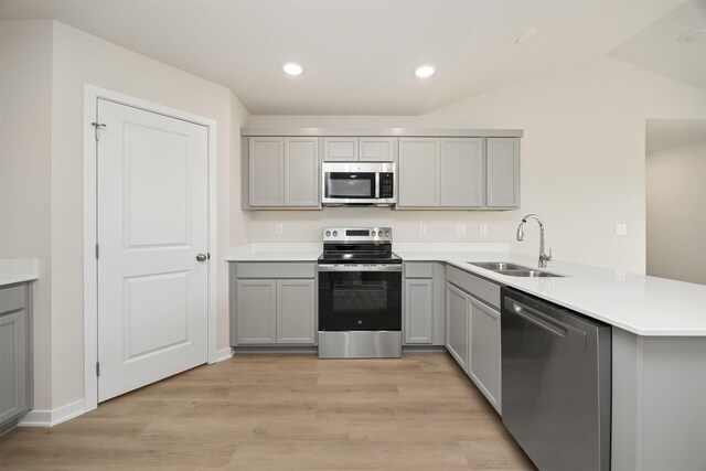 800 Linden St, Carlisle, IA 50047 - kitchen with stainless steel appliances, gray cabinets, a sink, a peninsula, and light wood-style floors