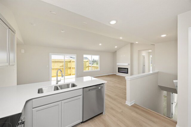 kitchen with stove, vaulted ceiling, sink, light hardwood / wood-style flooring, and dishwasher