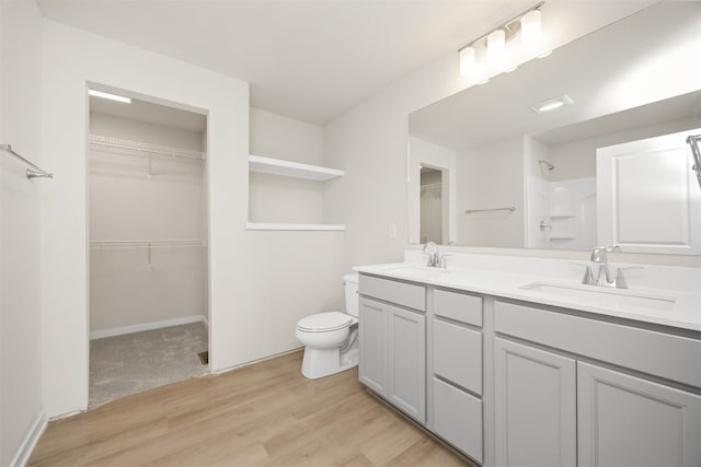 bathroom with hardwood / wood-style flooring, vanity, toilet, and walk in shower