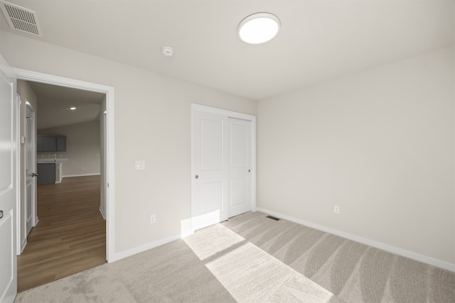 unfurnished bedroom with a closet and light colored carpet