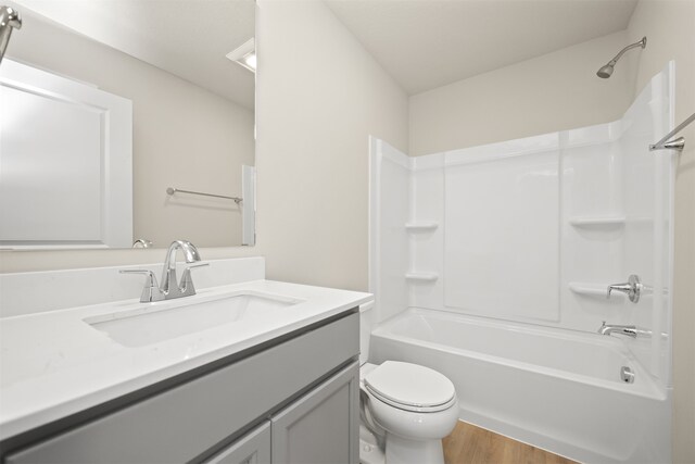 full bathroom featuring hardwood / wood-style floors, vanity,  shower combination, and toilet