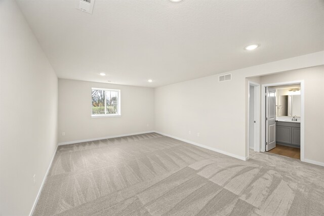 spare room with sink and light colored carpet