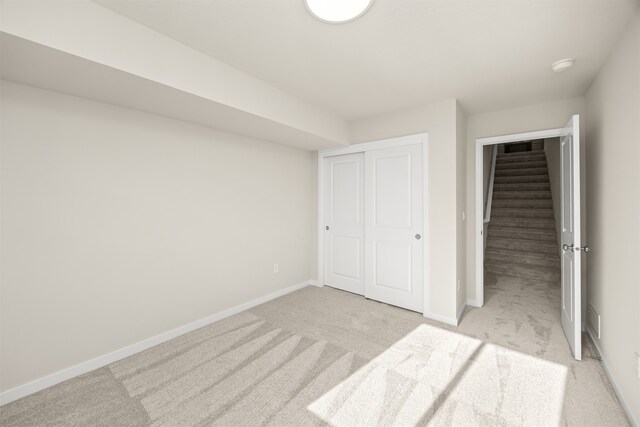 unfurnished bedroom featuring light colored carpet and a closet