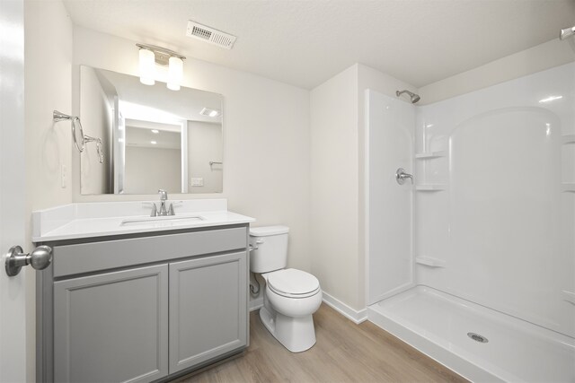 bathroom featuring a shower, hardwood / wood-style floors, vanity, and toilet