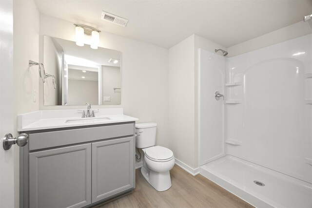 800 Linden St, Carlisle, IA 50047 - bathroom featuring wood finished floors, toilet, vanity, baseboards, and a shower