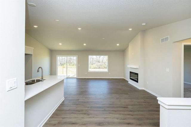 6570 NE 11th Ct, Des Moines, IA 50313 - unfurnished living room with a sink, dark wood-style flooring, a large fireplace, baseboards, and recessed lighting