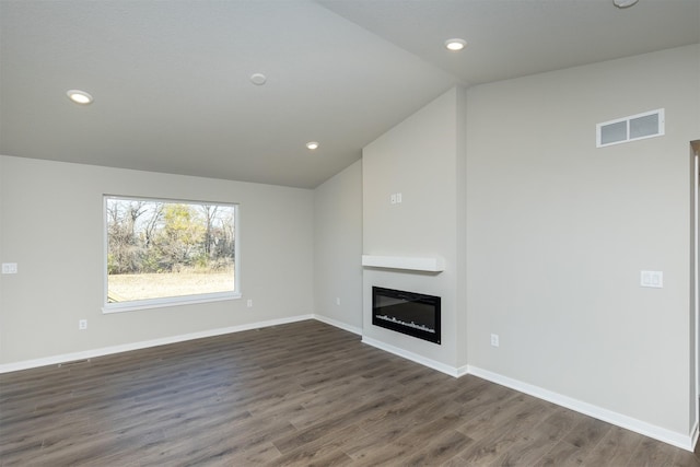 6570 NE 11th Ct, Des Moines, IA 50313 - unfurnished living room with dark wood-type flooring, a glass covered fireplace, lofted ceiling, recessed lighting, and baseboards