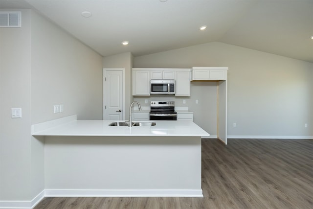 6570 NE 11th Ct, Des Moines, IA 50313 - kitchen featuring appliances with stainless steel finishes, a sink, vaulted ceiling, wood finished floors, and white cabinets