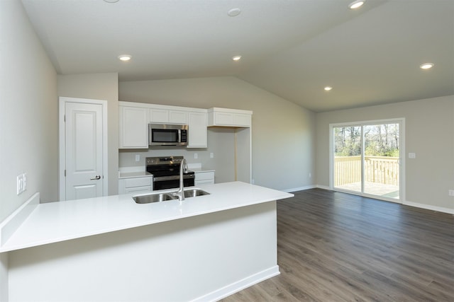 6570 NE 11th Ct, Des Moines, IA 50313 - kitchen with stainless steel appliances, a sink, white cabinetry, lofted ceiling, and wood finished floors