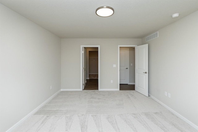 6570 NE 11th Ct, Des Moines, IA 50313 - unfurnished bedroom with light carpet, baseboards, a spacious closet, and a closet