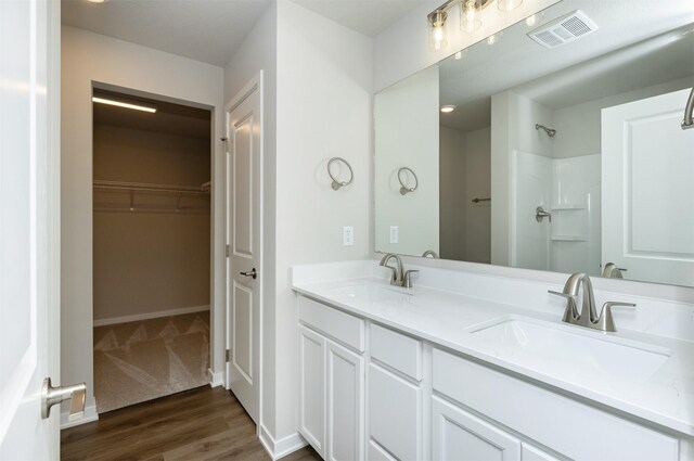 6570 NE 11th Ct, Des Moines, IA 50313 - full bath featuring double vanity, wood finished floors, a spacious closet, a shower, and baseboards