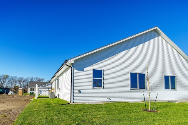 view of side of property featuring central air condition unit and a yard