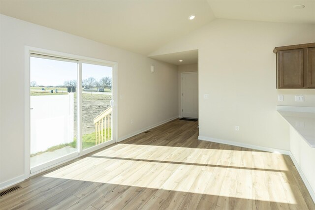 6573 NE 11th Ct, Des Moines, IA 50313 - unfurnished living room featuring light wood-style flooring, lofted ceiling, baseboards, and recessed lighting