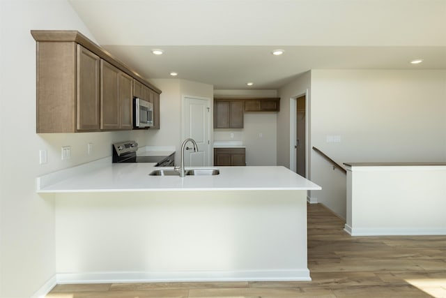 6573 NE 11th Ct, Des Moines, IA 50313 - kitchen featuring appliances with stainless steel finishes, a peninsula, a sink, recessed lighting, and light wood finished floors