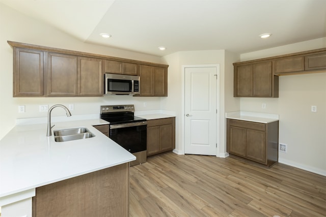 kitchen with stainless steel appliances, sink, light wood-type flooring, and kitchen peninsula