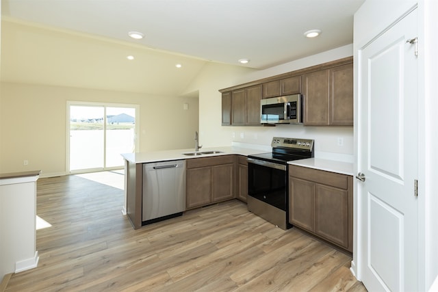 kitchen featuring stainless steel appliances, light wood-type flooring, sink, kitchen peninsula, and lofted ceiling