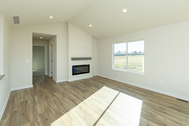 unfurnished living room featuring vaulted ceiling and light hardwood / wood-style floors
