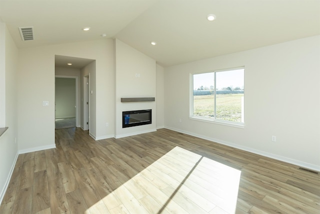 6573 NE 11th Ct, Des Moines, IA 50313 - unfurnished living room with light wood-style flooring, a glass covered fireplace, baseboards, vaulted ceiling, and recessed lighting