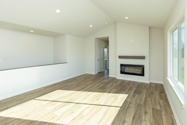 6573 NE 11th Ct, Des Moines, IA 50313 - unfurnished living room featuring wood finished floors, plenty of natural light, a glass covered fireplace, baseboards, and lofted ceiling