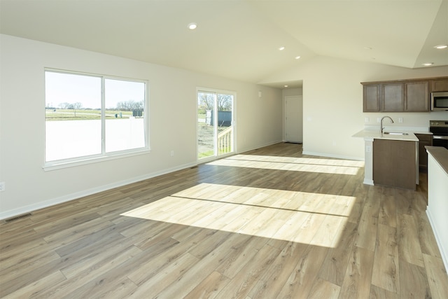 interior space with lofted ceiling, sink, and light hardwood / wood-style flooring