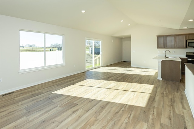 6573 NE 11th Ct, Des Moines, IA 50313 - kitchen featuring appliances with stainless steel finishes, open floor plan, light countertops, lofted ceiling, and light wood-type flooring