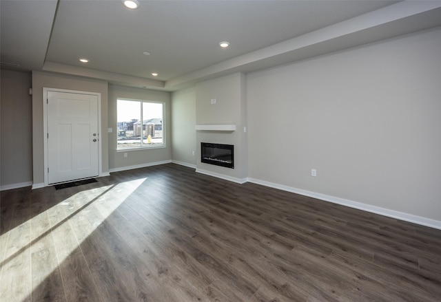 unfurnished living room with a raised ceiling and dark hardwood / wood-style floors