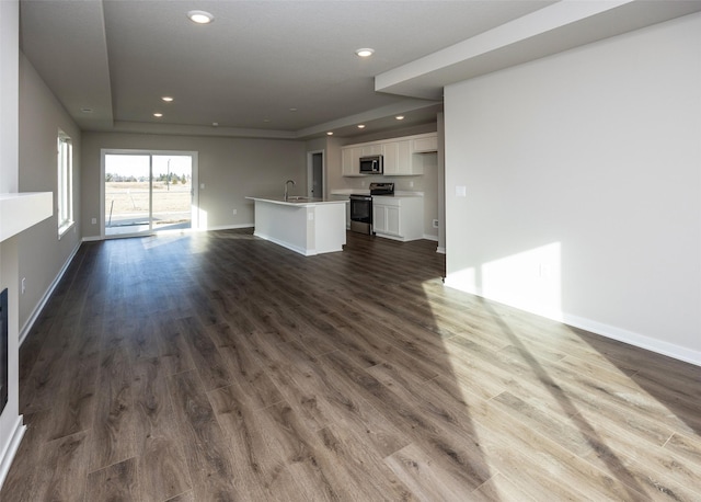 unfurnished living room featuring dark hardwood / wood-style flooring, sink, and a tray ceiling