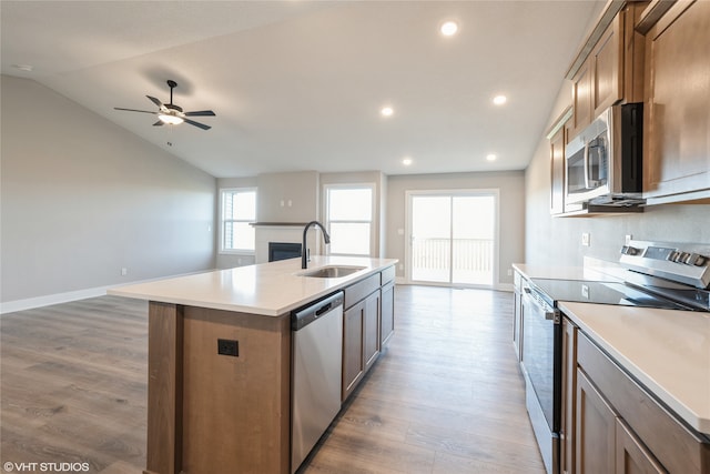 kitchen featuring lofted ceiling, an island with sink, appliances with stainless steel finishes, light hardwood / wood-style floors, and sink