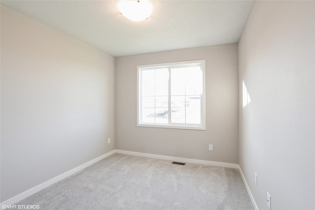 empty room with a textured ceiling and light colored carpet