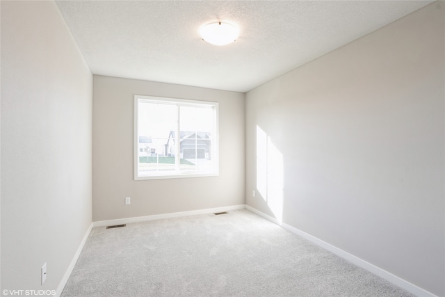 spare room featuring light carpet and a textured ceiling