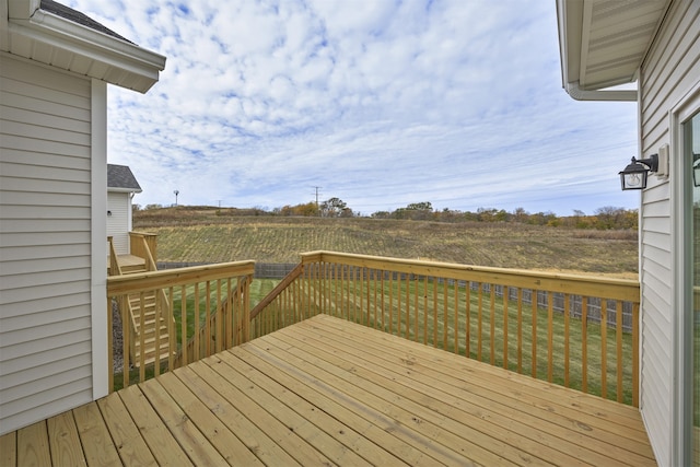 wooden terrace featuring a lawn and a rural view