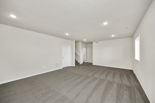 empty room with a textured ceiling and dark carpet