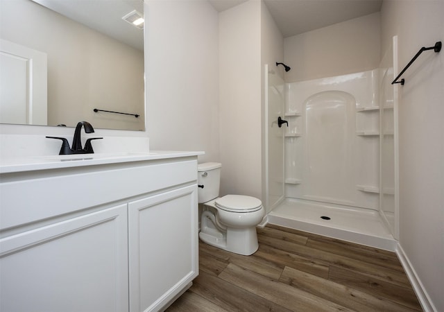 bathroom featuring toilet, vanity, wood-type flooring, and walk in shower