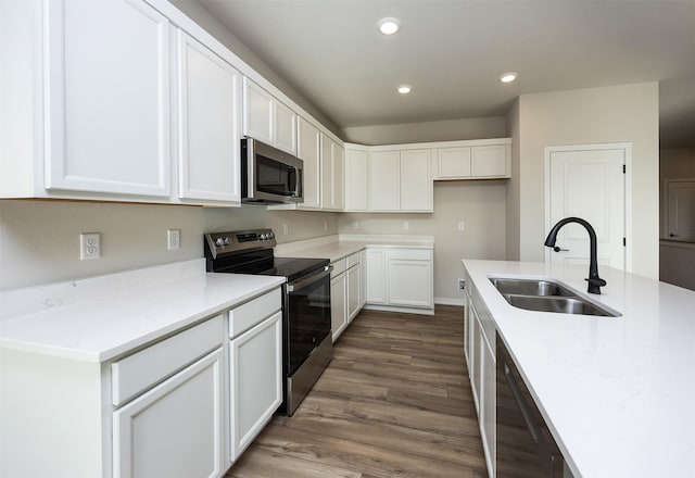 kitchen with dark wood-type flooring, white cabinets, sink, appliances with stainless steel finishes, and light stone counters