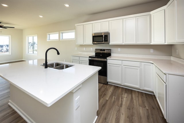 kitchen with dark hardwood / wood-style flooring, sink, stainless steel appliances, and an island with sink