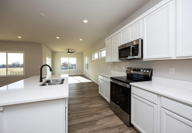 kitchen with ceiling fan, sink, dark hardwood / wood-style flooring, a kitchen island with sink, and appliances with stainless steel finishes