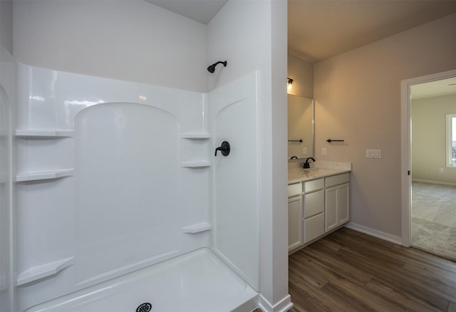 bathroom featuring hardwood / wood-style flooring, vanity, and a shower