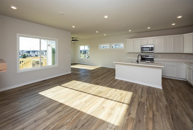 kitchen with sink, dark wood-type flooring, an island with sink, white cabinets, and appliances with stainless steel finishes