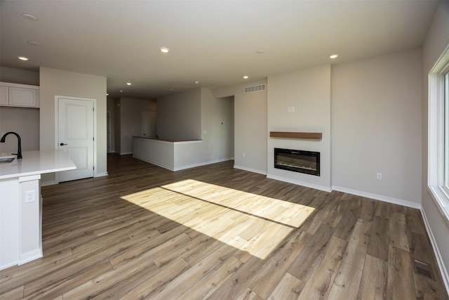 unfurnished living room with hardwood / wood-style floors and sink