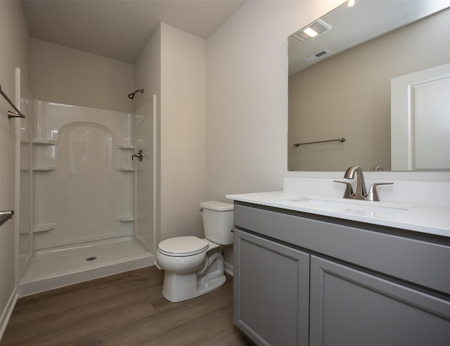 bathroom featuring hardwood / wood-style floors, vanity, toilet, and a shower