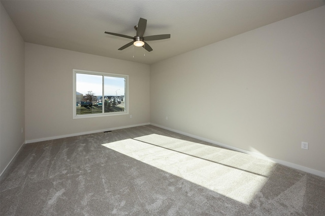 spare room with ceiling fan and dark carpet