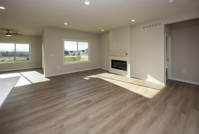 unfurnished living room with ceiling fan, plenty of natural light, and wood-type flooring