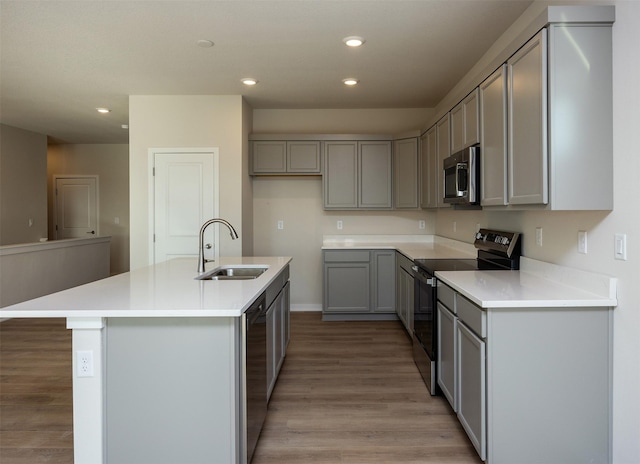 kitchen featuring appliances with stainless steel finishes, a kitchen island with sink, sink, light hardwood / wood-style flooring, and gray cabinets