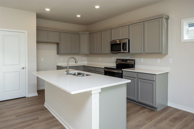 kitchen featuring gray cabinets, sink, stainless steel appliances, and a kitchen island with sink