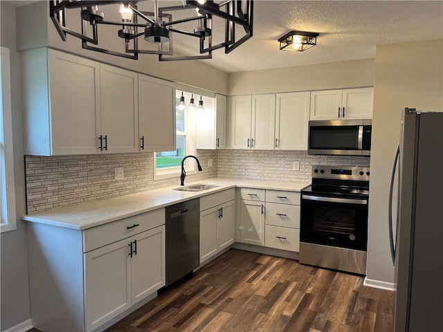 kitchen with stainless steel appliances, sink, backsplash, white cabinetry, and dark wood-type flooring