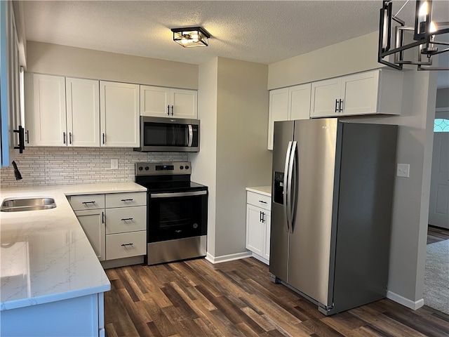 kitchen featuring white cabinets, stainless steel appliances, light stone countertops, and dark wood-type flooring