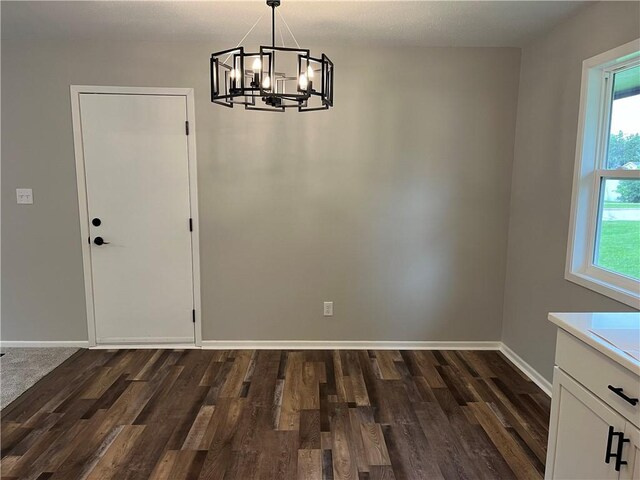 unfurnished dining area featuring dark wood-type flooring and a chandelier