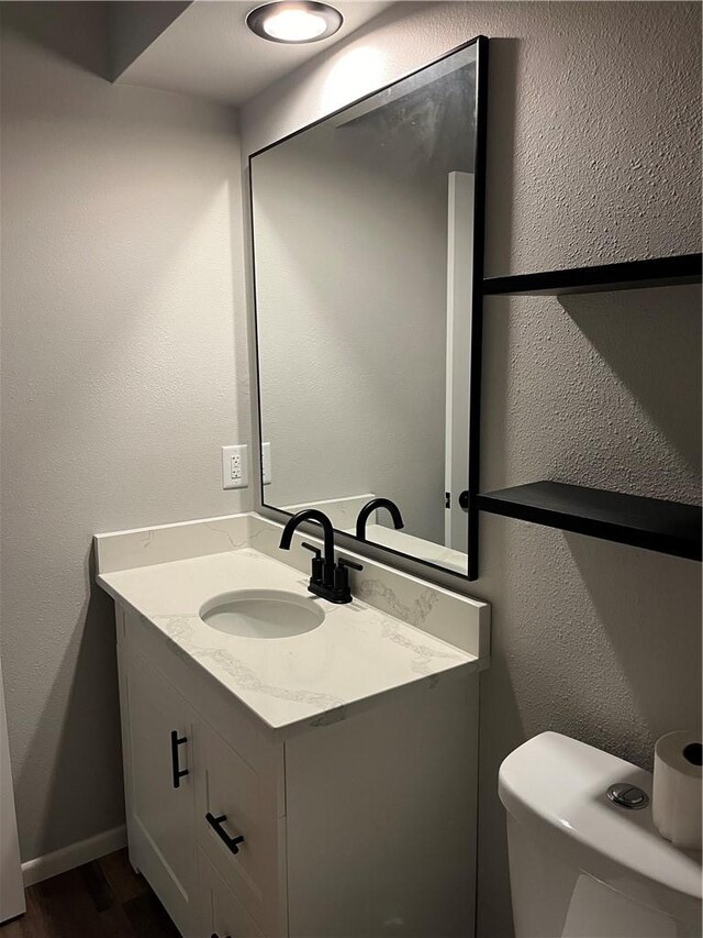 bathroom with vanity, wood-type flooring, and toilet