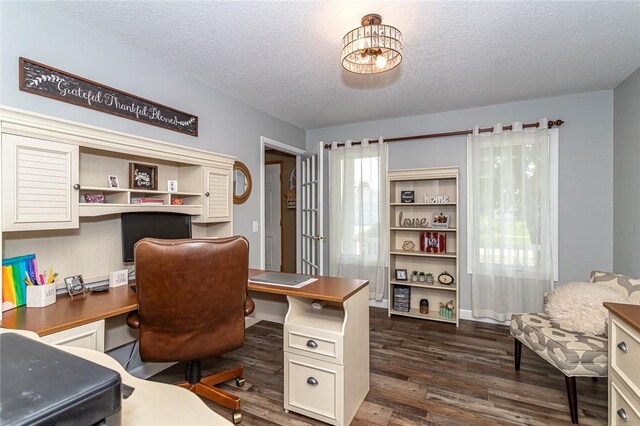 office space with a textured ceiling, dark hardwood / wood-style floors, and built in desk