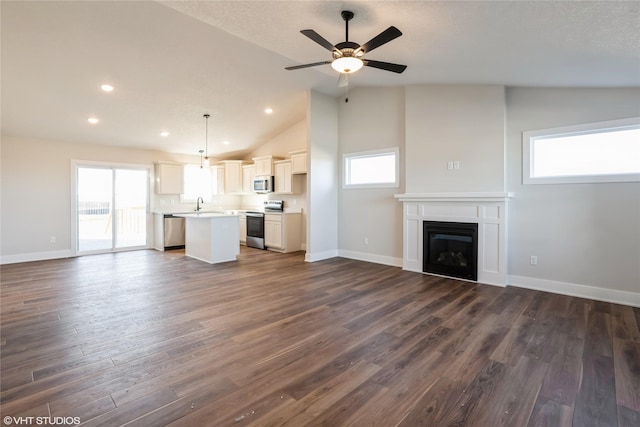 unfurnished living room with plenty of natural light, lofted ceiling, and dark wood-type flooring